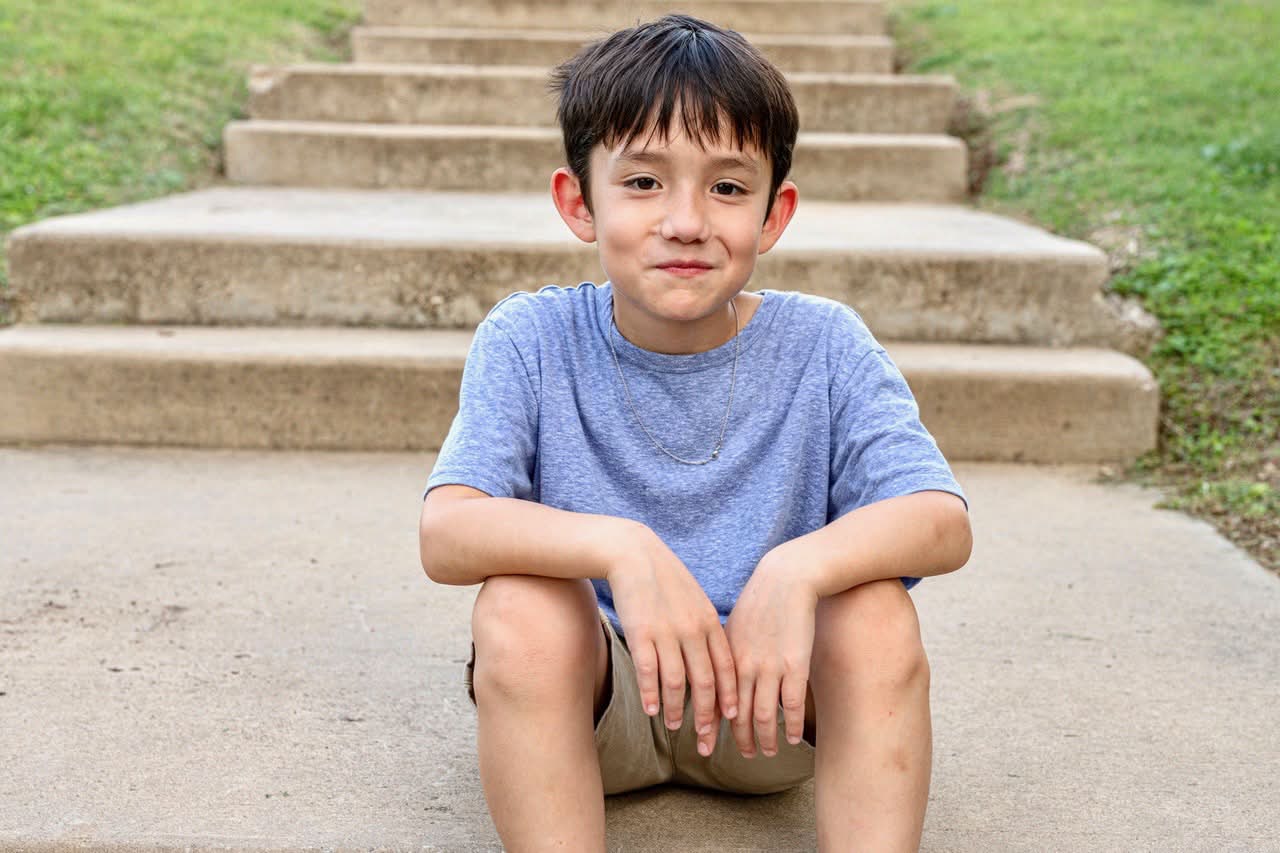 Child portrait seated on steps smiling softly